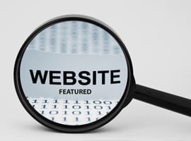 Graphic of a magnifying glass looking at a keyboard with text that says WEBSITE Featured