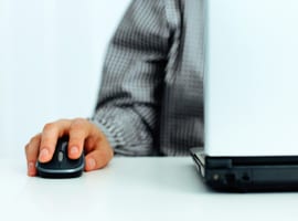 Man with hand on mouse using a laptop
